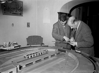 836634 Afbeelding van de heer H. de Groot (rechts) bij zijn modelspoorbaan in de woonkamer van zijn huis aan de Justus ...